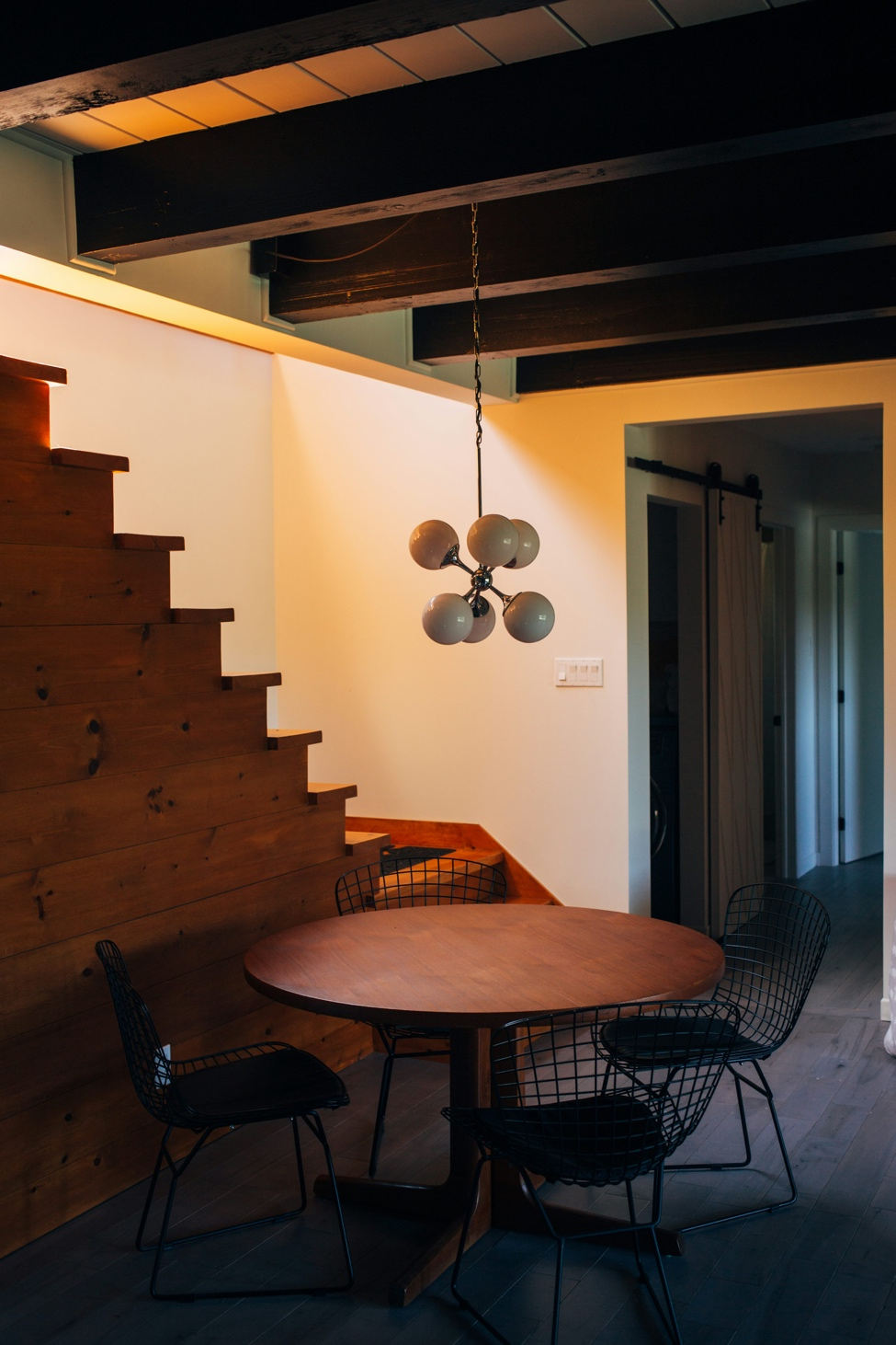 Modern basement renovation with a stylish round wooden table, chairs, and a white pendant lamp