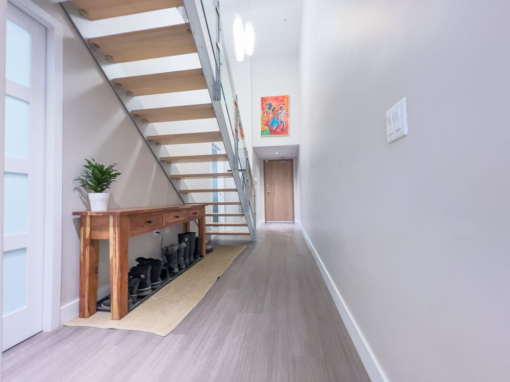 Bright basement hallway with floating stairs and accent lighting